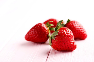 Ripe red strawberry on a pink wooden table