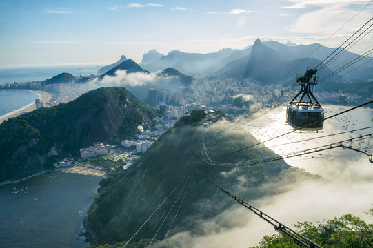 Bright misty view of the city skyline of Rio de Janeiro, Brazil with a Sugarloaf (Pao de Acucar) Mountain cable car passing in the foreground