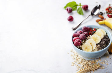 Healthy breakfast. Home made oatmeal porridge, goji berries, pumpkin and chia seeds  in a ceramic bowl on white background.