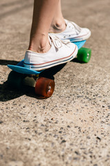 Young girl in sneakers on skateboard.