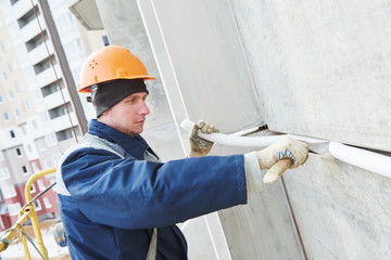 Facade plasterer sealing joint of building wall with putty mastic 