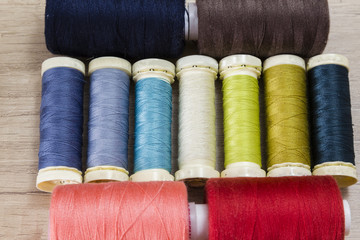 Several spools of thread of different colors and sizes on a wooden table
