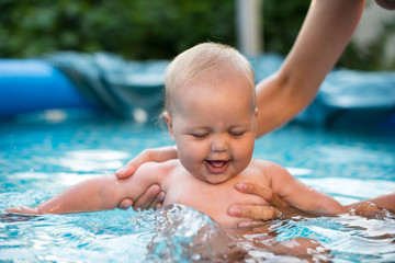 A cute happy young female girl child baby relaxing on the side of a swimming pool