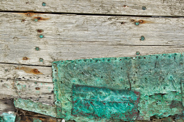 detailed shot of green metal nailed on wooden plank.