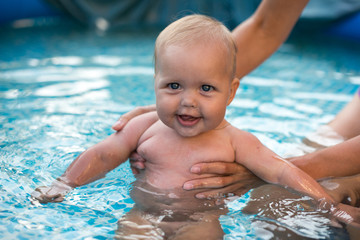 A cute happy young female girl child baby relaxing on the side of a swimming pool