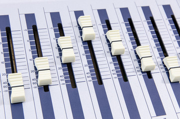 closeup of music mixer knobs in a metallic casing forming a wave curve