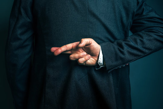 Lying businessman holding fingers crossed behind his back - Powered by Adobe