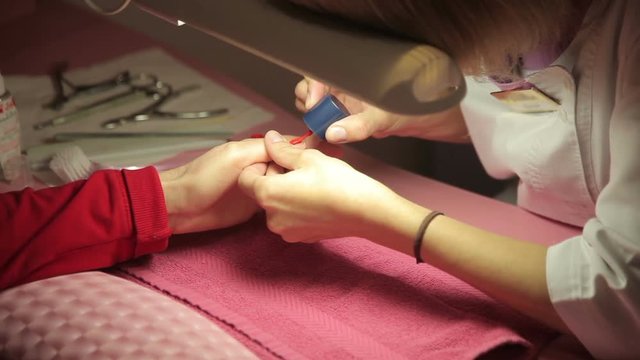 Master makes the girl manicure hands at salon