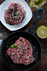 Above view of raw fresh tuna steaks covered with sesame seeds