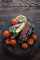 Rustic wooden serving board with roasted tuna fillet, closeup