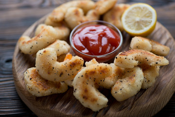 Wooden serving board with fried breaded shrimps, closeup