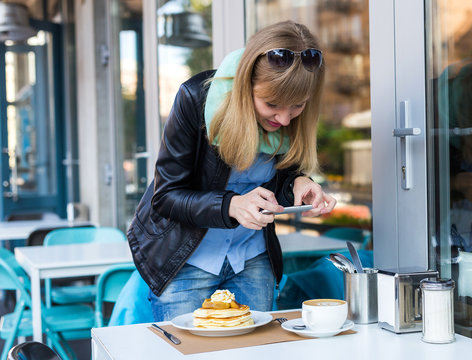 Woman taking picture of her coffee shop breakfast