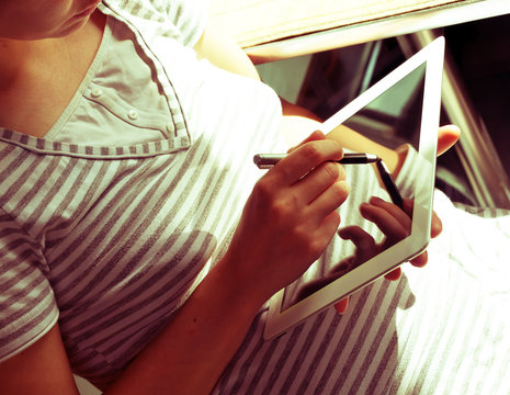 Girl in a striped shirt with a tablet computer and a stylus. Soft and sunny. With reflection. Retro effect.