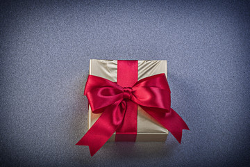 Present box with red ribbon on grey background holidays concept