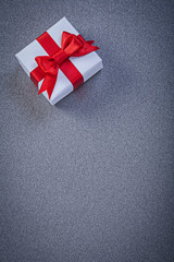 White boxed present with red knot on grey surface copyspace holi