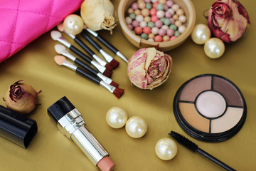 Obraz na płótnie Canvas Cosmetics set for makeup and decorations on the gold background