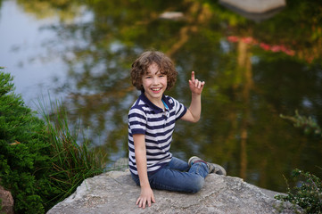 Boy sitting on a boulder near the water