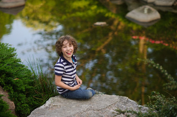 Boy sitting on a boulder in the small pond