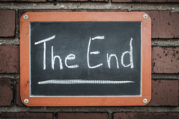 Tafel an einer Ziegelwand mit Text / Tafel an einer Ziegelwand mit Text The End.
