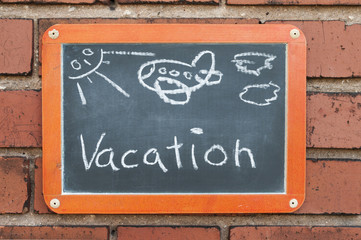 Tafel an einer Ziegelwand mit Text / Tafel an einer Ziegelwand mit Text Vacation.
