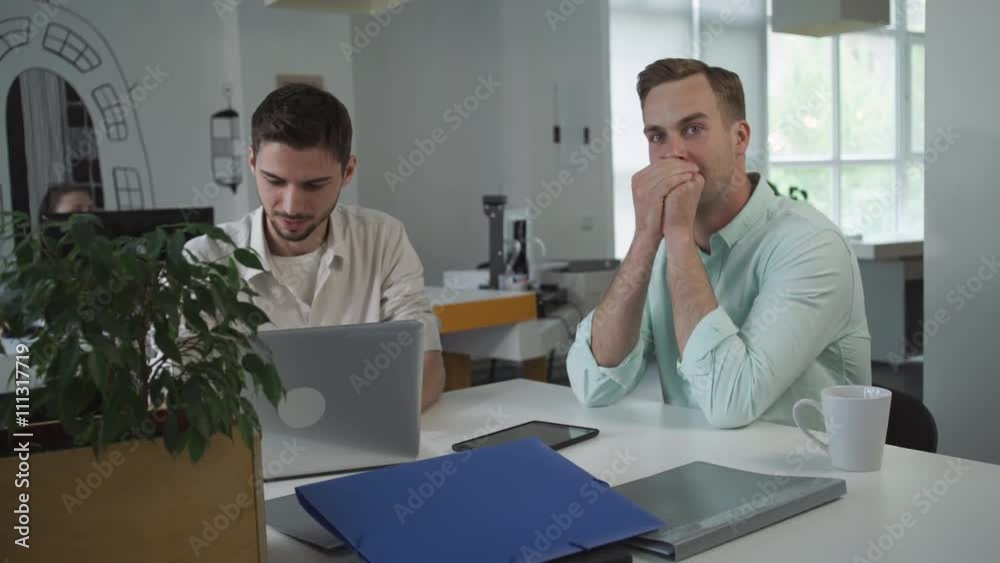 Poster young happy man laughs. men have fun at the working place in the office. beginner writer working on 