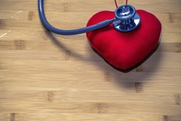 Red heart and a stethoscope on wood background. take care of heart Concept.
