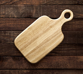 Cutting board on dark wooden table, top view
