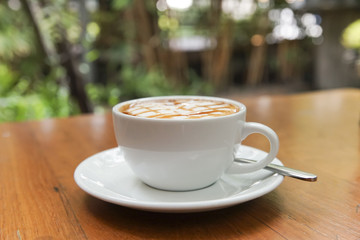 Soft focus of hot caramel macchiato on wooden table.