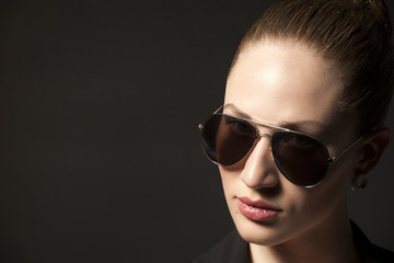 Portrait of Beautiful young woman in sunglasses on black backgro