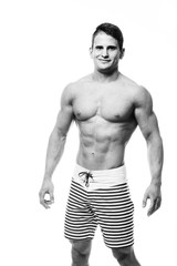 Sexy athletic man showing muscular body and sixpack abs, isolated over white background. Strong male nacked torso. Monochrome photo.
