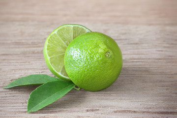  limes, slice and leaves on wooden board