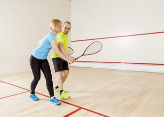 Male coach coaching squash beautiful young blond woman