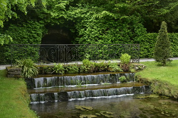 Fototapeta na wymiar Les mini cascades au bout du canal inférieur au milieu d'une décoration luxuriante aux Jardins d'Eau d'Annevoie