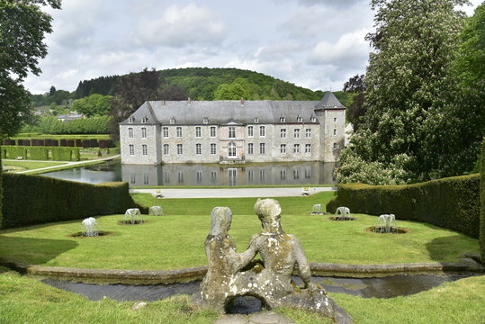 Statue en pierre dominant la série de fontaines dans l'herbes en face du château de Rouillons aux Jardins d'Eau d'Annevoie 