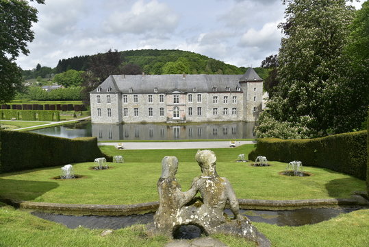 Statues en pierre et fontaines dans l'herbe en face du château de Rouillons dans une nature verdoyante aux Jardins d'Eau d'Annevoie