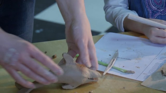 Female Hands Put a Dolphin Sculpture to a Table Kid Cut Out Shaped a Sculpture Clay Figurine With a Teacher's Help Learing a Pottery Craft Pottery Workshop