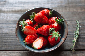 Fresh red sweet strawberries in old clay bowl close-up. Flat Lay of strawberry on wooden table. Concept of village life. Top view
