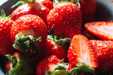 Bunch of fresh strawberries halves and wholes. With green strawberry stalks. Fresh, tasty red...
