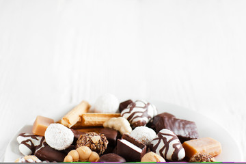Assorted sweets on white background. Candies and cookies close-up. Chocolate candies on white background. Top view with copy space