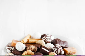 Wall murals Sweets Assorted sweets on white background. Candies and cookies close-up. Chocolate candies on white background. Top view with copy space