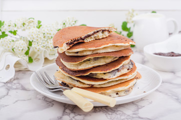 Stuffed chocolate pancakes on n vintage slate chalk board background with flowers and coffee cup. Selective focus
