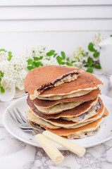 Stuffed chocolate pancakes on n vintage slate chalk board background with flowers and coffee cup. Selective focus