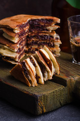 Stuffed chocolate pancakes on n vintage slate chalk board background with flowers and coffee cup. Selective focus