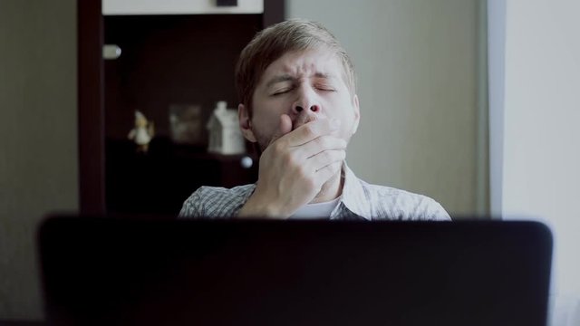 young guy bored in front of the laptop
