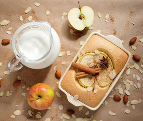 Fototapeta na wymiar Homemade apple cake and a jug with milk on a paper background, top view, baking concept