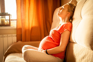 Serene woman during pregnancy relaxing at home with closed eyes - obrazy, fototapety, plakaty