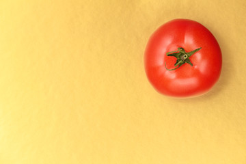Top view of a red juicy tomato on a gold background. Bright and juicy tomato in the top right corner of the image. Tasty tomato. Tomato wallpaper. Tomato menu. Tomato poster. Vegetable texture
