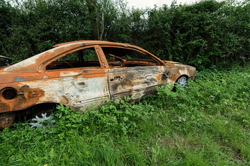 Burnt out & abandoned rusty old car by side of road