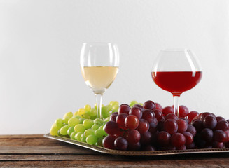 Wine and grape on wooden table against light background
