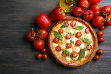 Pizza Margherita with arugula, red pepper, tomatoes on wooden table